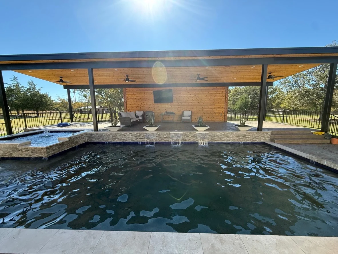 Large custom pool with covered pavilion, waterfall detail, and outdoor lounge by Averra Pools and Outdoor Living